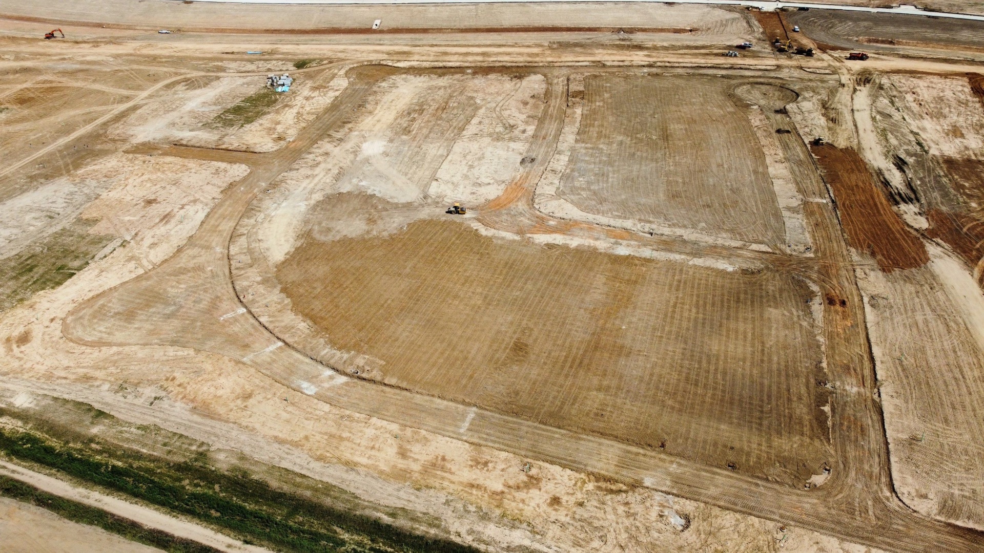 Excavator performing mass grading on construction site